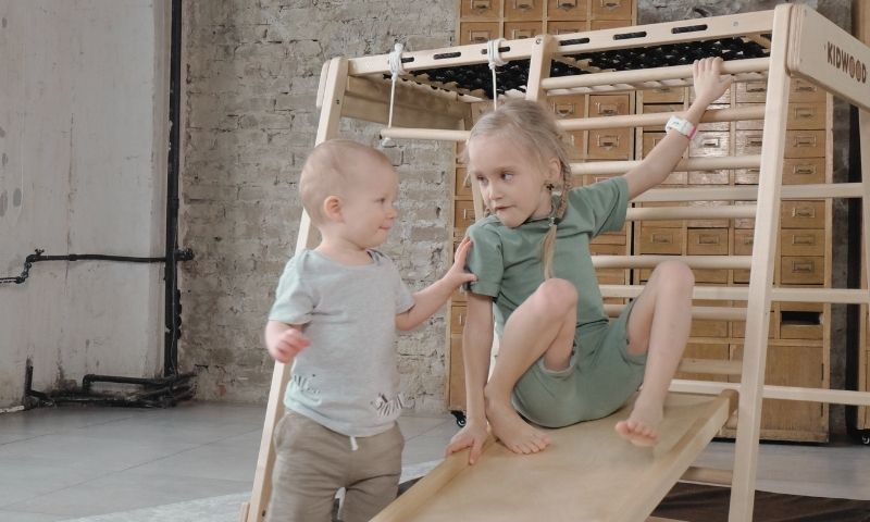 Pieni poika ja tyttö leikkivät Kidwood-liikuntaleikkipaikassa.